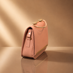 Pink handbag with gold accents on a reflective surface and beige background