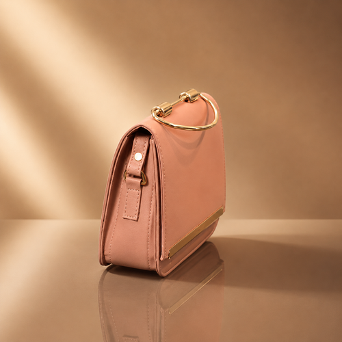 Pink handbag with gold accents on a reflective surface and beige background