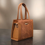 Brown leather handbag on a reflective surface with a neutral background