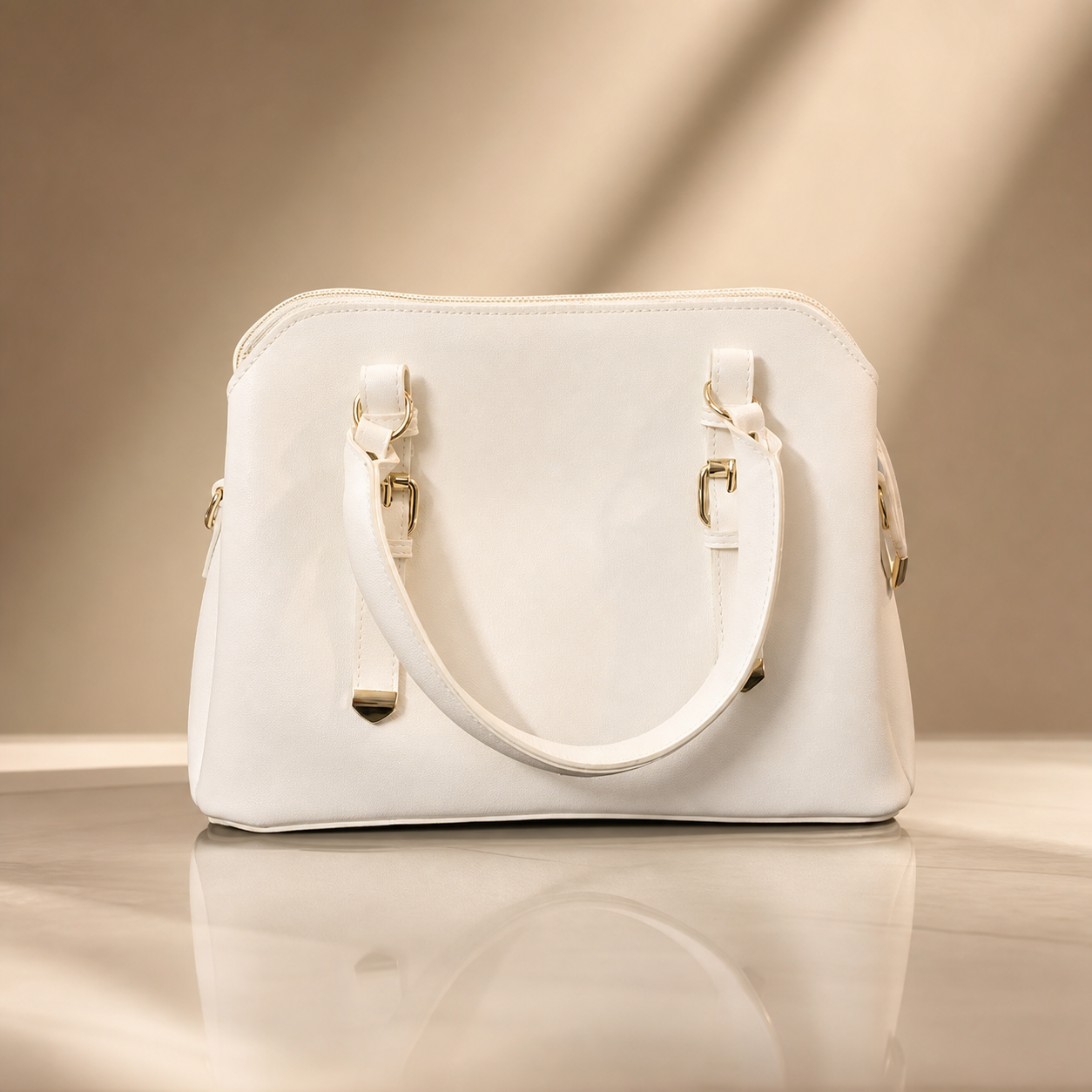 White handbag with gold accents on a reflective surface and beige background